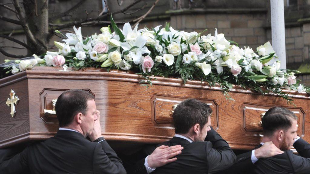 Coffin being lifted by gentlemen